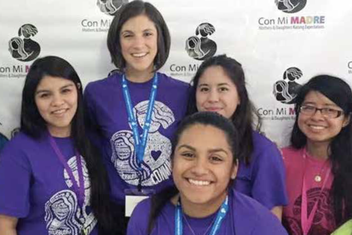 Con Mi Madre Executive Director Dr. Teresa Granillo smiles for the camera with a group of college-bound young Latinas. 