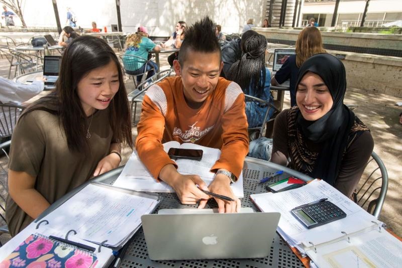 A group of smiling students studying outside