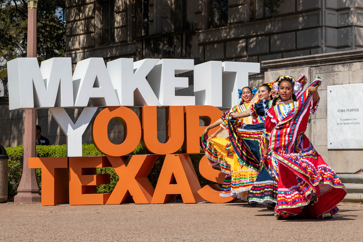Make It Your Texas sculpture with three traditionally-dressed Latina dancers