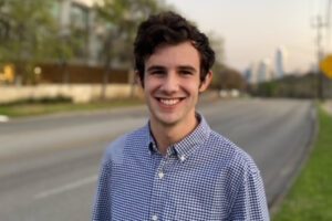 Picture of Cole Glosser, President of UT Austin's Disability Advocacy Student Coalition (DASC), standing outside by a roadway